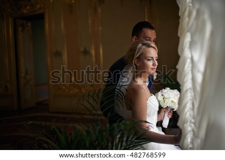 married couple stand near the window