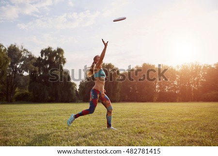 Young athletic girl playing with flying disc, ultimate