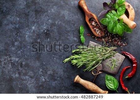 Herbs and spices cooking on stone table. Basil, rosemary, pepper and salt. Top view with copyspace 