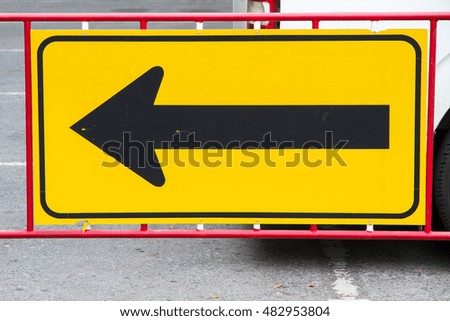Yellow arrow road sign by the left side of the road