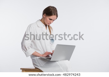 Smiling female doctor working on her laptop against a white background