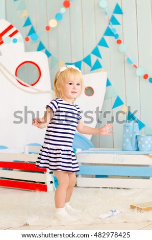 blond girl in a striped dress stands on a decorative background ship