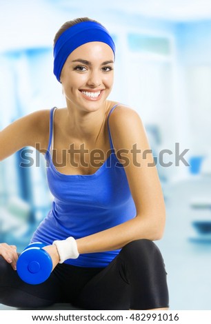 Young happy woman doing exercise, at fitness club or center