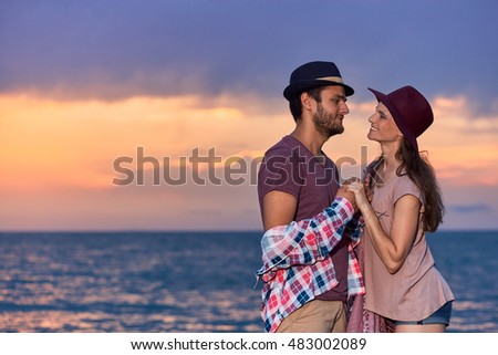 Twilight. Beautiful picture of couple in love under the sunset background on the beach.