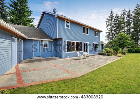 Blue house backyard with concrete floor patio area and well kept garden. Northwest, USA
