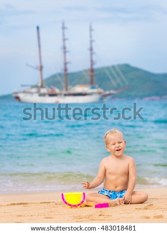 Cute boy on the tropical beach playing toys