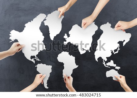Group of human hands holding with jigsaw puzzle forming in world map Dark texture background. teamwork concept.