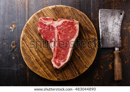 Raw fresh meat T-bone steak and Butcher cleaver on chopping cutting board on wooden background Royalty-Free Stock Photo #483044890