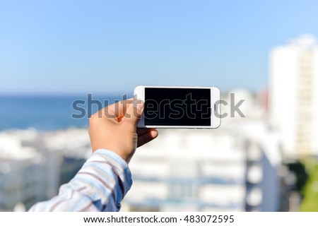 Closeup on smartphone in the hand with blue sky on the background