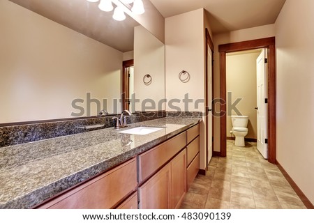 Luxury bathroom interior with vanity cabinet with granite counter top and large mirror. View toilet and tile floor. Northwest, USA