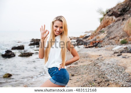 Smiling beautiful young woman showing ok sign on the beach