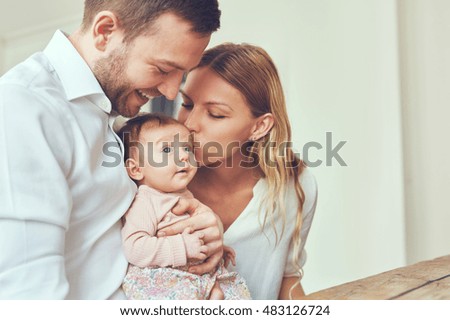 Smiling mother and father holding their newborn baby daughter at home Royalty-Free Stock Photo #483126724