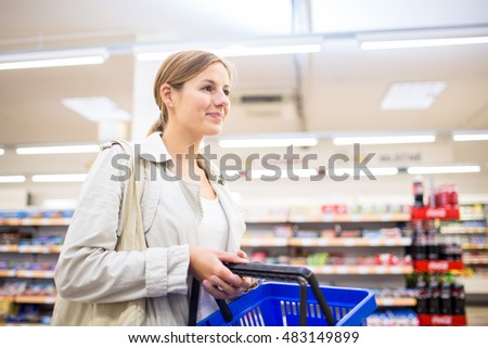 Beautiful young woman shopping in a grocery store/supermarket (color toned image). Waiting in the queue