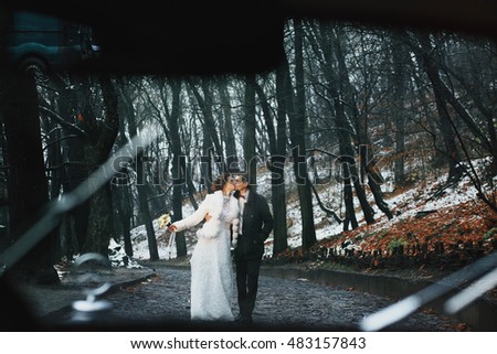 beautiful and happy newlyweds walking in rainy weather