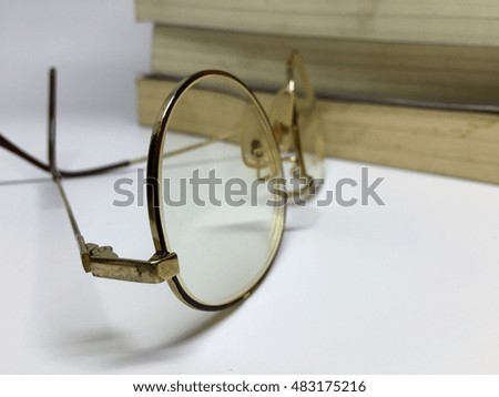 A glasses on white table with books mountain