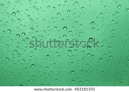 Water drops on glass with light green background