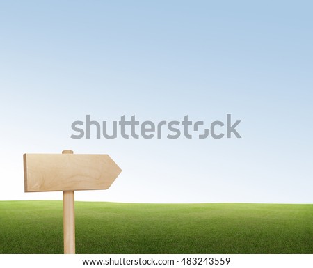 wooden sign on the left side of a green land with a blue sky