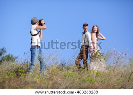 a wedding photographer takes pictures of the bride and groom in nature, the photographer in action