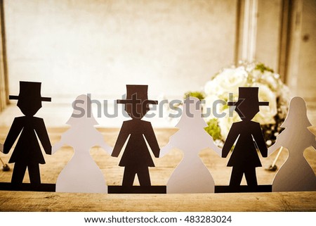 Bride and Groom Paper Doll Cut Outs Lined Up on Rustic Wooden Table in front of White Rose Bridal Bouquet - Decorations at Wedding or Bridal Shower in Newlywed Concept Image