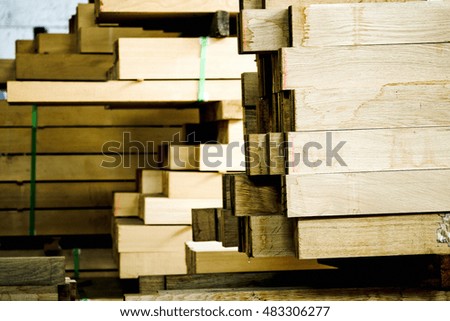 A picture of stacked wooden poles in a warehouse. Raw materials for construction, interior decorators and furniture makers. Carpentry.