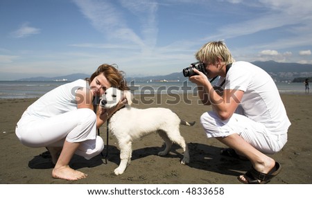 young couple on the beach with dog in taking pictures