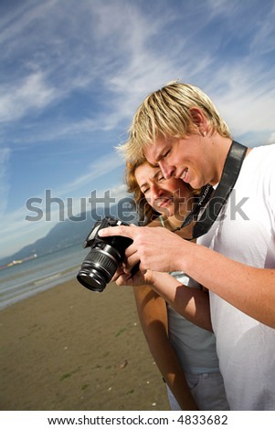 young couple on the beach taking pictures