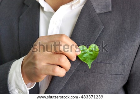 Businessman holding a green heart leaf / Business with corporate social responsibility and environmental concern                                Royalty-Free Stock Photo #483371239