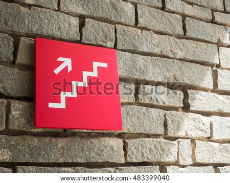 red stairs going up sign on wall brick background