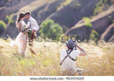 a wedding photographer takes pictures of the bride and groom in nature, the photographer in action