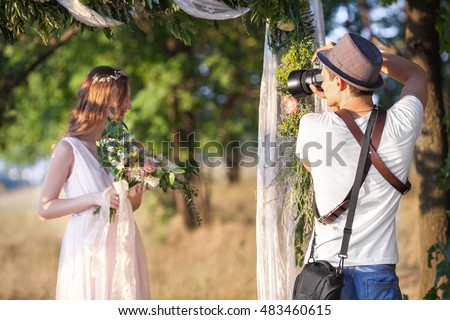 a wedding photographer takes pictures of the bride  in nature, the photographer in action