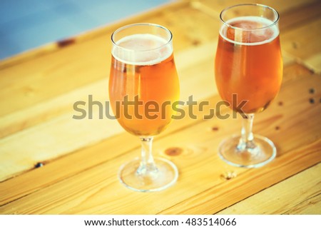 Beautiful background of the Oktoberfest. Two glasses of cold fresh light beer on the wooden bar counter in the pub. Assorted alcohol in a Flight Ready for Tasting