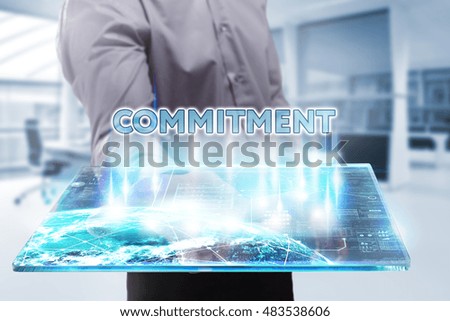 Business, Technology, Internet and network concept. Young businessman working on a tablet of the future, he sees the inscription: commitment