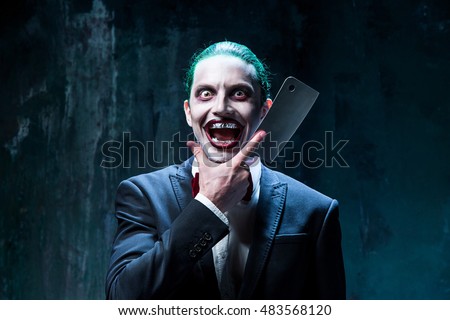 Bloody Halloween theme: The crazy joker face on black background with knife