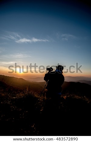 silhouette of photographer taking picture of landscape during sunrise