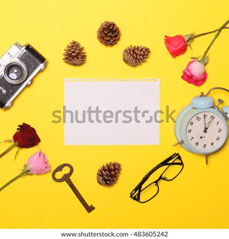 Blank paper with various objcects around it on yellow background - Trendy minimal flat lay concept