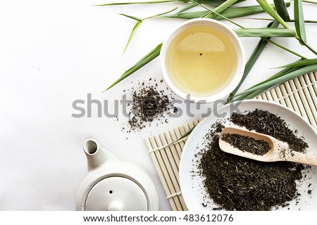 teapot and cup of herbal green tea on bamboo with white table background. over light Royalty-Free Stock Photo #483612076