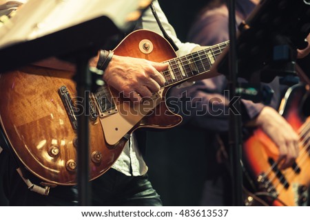 Rock and roll music background, guitar players on a stage, selective focus and  retro tonal correction filter, old instagram style Royalty-Free Stock Photo #483613537