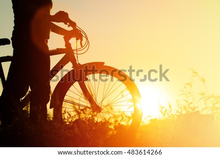 silhouette of young woman riding bike at sunset