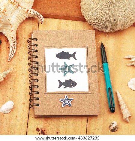 An empty,  note book with leather journal, pen and shells on a wooden desk top background