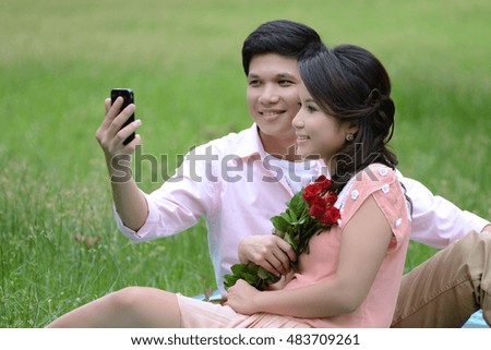 Couple man and woman looking mobile phone at park 
