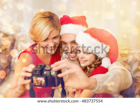 family, christmas, x-mas, winter, happiness and people concept - smiling family in santa helper hats taking picture with photo camera