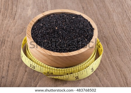 black sesame seeds in wooden bowl on wood background
