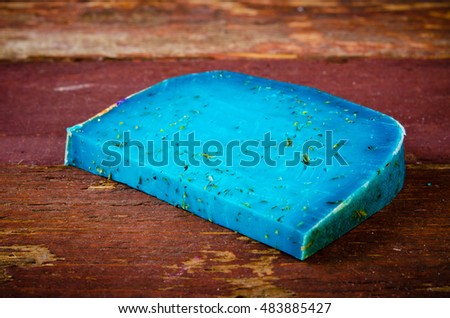 Blue pesto cheese with herbs on wooden rustic background.