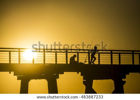 Silhouette of Father and Son Fishing On A Pier