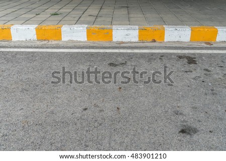 Concrete sidewalk with yellow and white curb