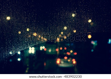 Vintage style - Rain drops on window with road light bokeh, City life in night in rainy season  abstract background,water drop on the glass, night storm raining car driving concept.