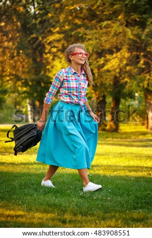 Young girl walking with a backpack in the hands in a city park. Outdoor Activities on a sunny day.