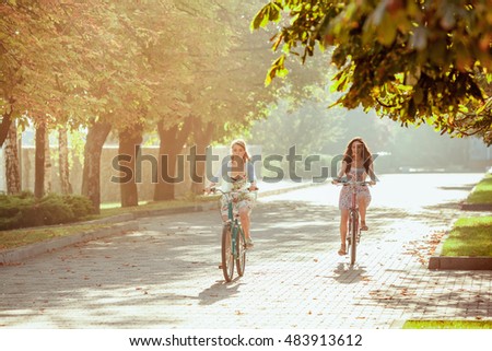 The two young girls with bicycles in park in summer