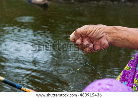 Older women using earthworms fishing villages  ,   shiny red worm impaled and writhing on a fishhook
