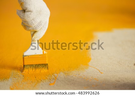 Hand with brush and yellow paint 